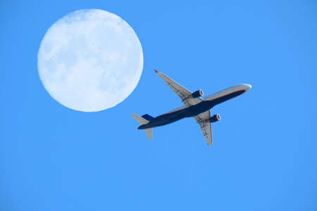 airplane flight against the full moon and blue sky, aviation and travel conceptの写真素材