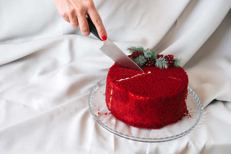 woman cut a red velvet cake on a plate textile backgroundの写真素材