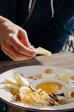 male hand with cheese slice and honey in a restaurantの写真素材