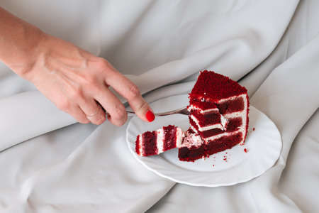 female hands with fork breaks red velvet cakeの写真素材