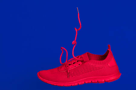 bright red running shoes levitate against a blue backgroundの写真素材
