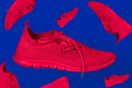 bright red running shoes levitate against a blue background