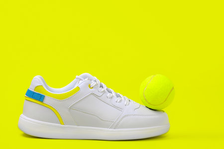 trendy white sneakers on a yellow background with tennis ball, copy spaceの写真素材