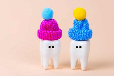 White tooth wearing knitted hat. Cute greeting card on a pastel background.の写真素材