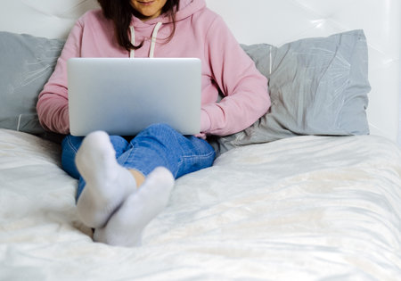 Young woman using laptop in the bedroom. Freelance and home office concept. Selective focus.の写真素材