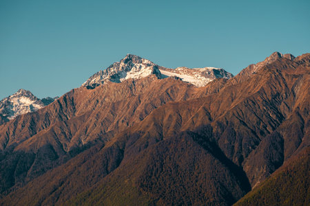 Beautiful brown mountains with snow-capped peaks against a blue sky. Natural wallpaper.の写真素材