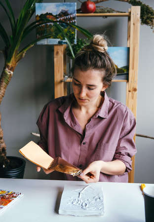 Young woman working with golden foil and plaster relief.の写真素材