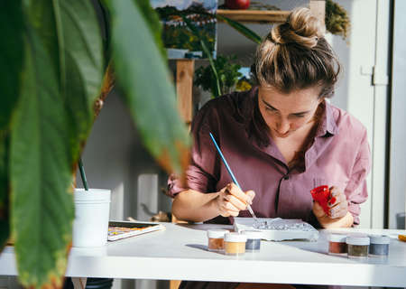 Young beautiful woman works with plaster relief and white paint. DIY and hobby concept.の写真素材