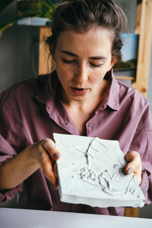 Young beautiful woman works with plaster relief. DIY and hobby concept.