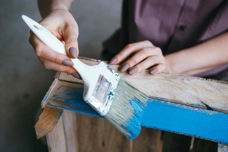 Close-up fwmale hands with brush painting wooden box. Handmade concept. Selective focus, blurredの写真素材