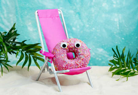 Funny summer card with donut relaxing on beach chair. Summer minimal food humor poster.の写真素材