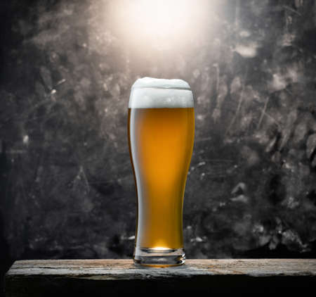 Glass of fresh beer on a wooden table on a background chalkboard in a barの写真素材