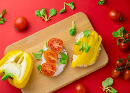 Top view toasts bell pepper, tomatoes and cottage cheese red background. Healthy food concept.の写真素材