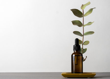 Cosmetic product brown glass jar with eucalyptus dry leaves on a gray background, copy space.の写真素材