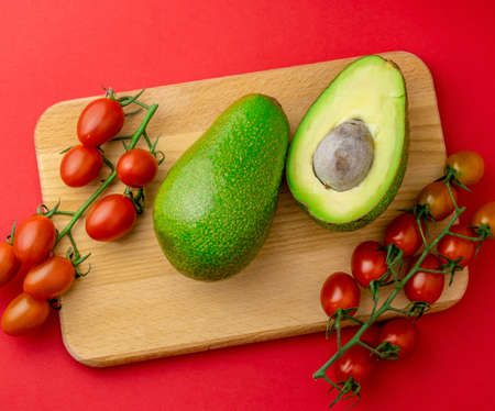 Top view flat lay avocado and cherry tomatoes red background. Organic healthy food.の写真素材