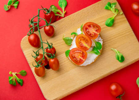 Top view flat lay toast with cottage cheese and sliced cherry tomatoes wooden board red background, healthy food conceptの写真素材