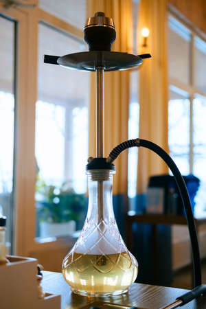 Close up hookah on a table with smoke on the background of a blurred restaurant hall. Smoking hookah concept.の写真素材