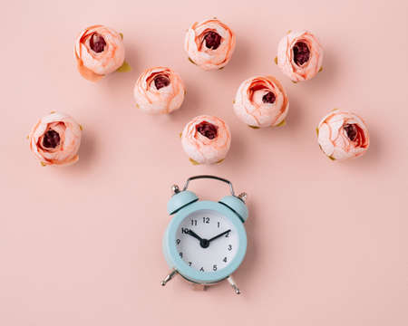 Top view flat lay alarm clock and roses soft pink background