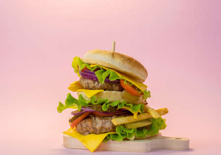 Big double meat burger on a pastel pink background. Fast food concept poster.の写真素材
