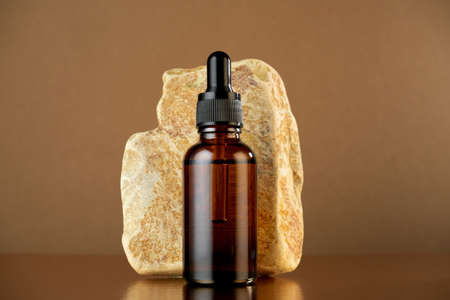 Beauty product on a stone stand on a brown background. Trendy skin beauty care poster.の写真素材