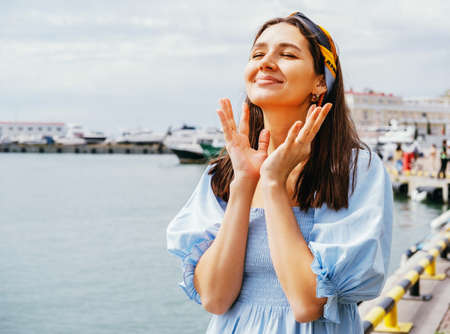 Pretty young woman lifestyle portrait on a background of blue sea. Summer travel concept.の写真素材