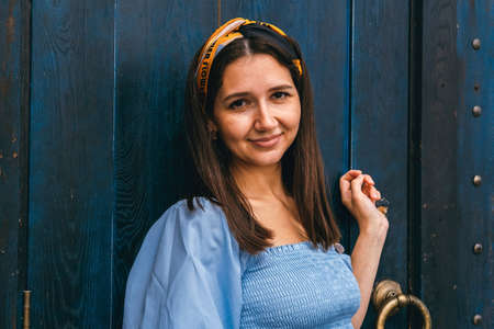 Young beautiful caucasian brunette woman portrait on a background of a blue door.の写真素材