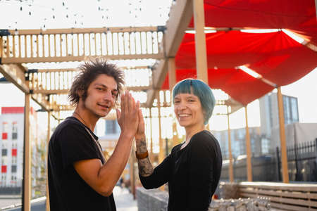 Young hipster guy and girl look at the camera give each other high five. Happy emotional portraitの写真素材