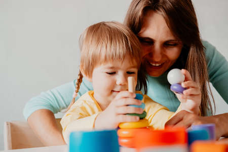 Close up portrait mother and daughter playing pyramid constructor toyの写真素材