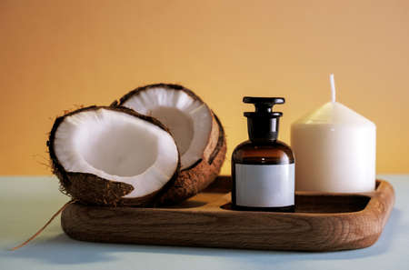 Spa composition with coconut, cosmetic product mock up bottle and white candle on a wooden tray.の写真素材