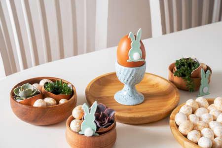 Easter set holiday table. White table with egg on egg stand.