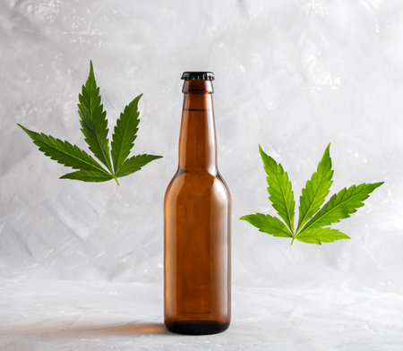 Bottle of beer and levitating green cannabis leaves on gray background.の写真素材