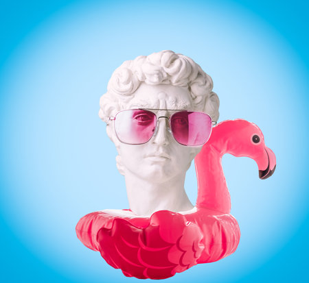 Collage of David's head with inflatable flamingo and pink glasses on blue background. Summer travel poster concept.の写真素材