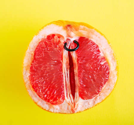 Top view half of grapefruit with piercing ring on yellow background.