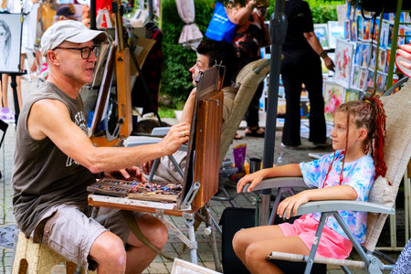 July 24, 2022, Sochi, Russia - Street artist paints a portrait of a little girl on the street.のeditorial素材