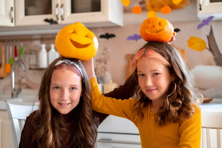 Two cute happy sisters holding Halloween pumpkins. Happy autumn lifestyle kids portrait.の写真素材