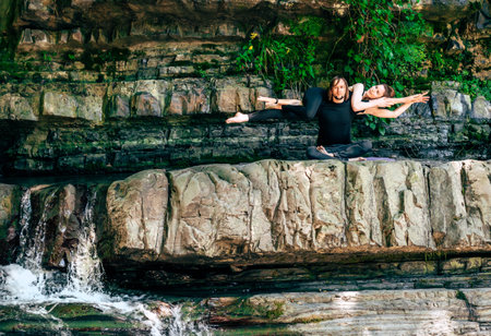 acroyoga. Young man holds his girlfriend in the forest near the waterfall. Active lifestyle concept.の写真素材