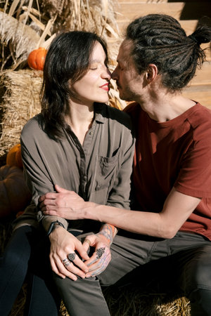 Young hipster couple kissing sitting on the steps on a sunny summer day.の写真素材