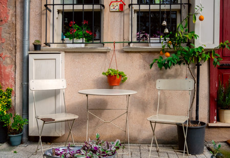 Table, chairs and potted plants on the balcony of an apartment building.の写真素材