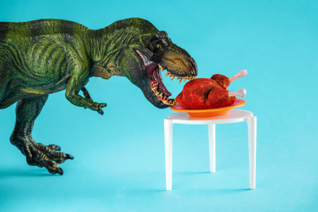 Dinosaur eats roast turkey on a blue background.の写真素材