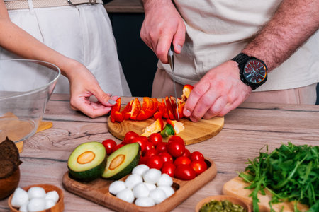 Close up female and male hands slicing pepper for vegetable salad.の写真素材