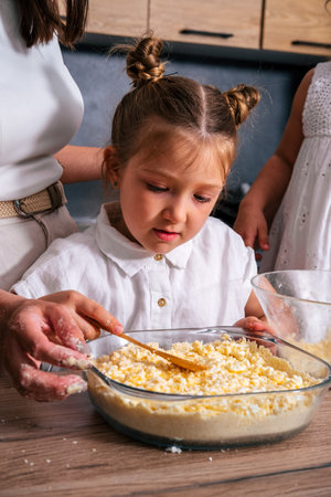 Little girl helps her mother to cook sweet cheesecake.の写真素材