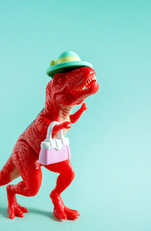 Cute red dinosaur in hat with little purse on blue background.の写真素材
