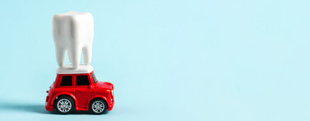 Miniature red car carries model of human tooth on roof on blue background. Advertising banner for...