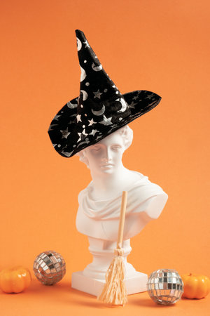 Modern still life with ancient statue wearing witch hat and holding broom. Creative minimal Halloween card.の写真素材