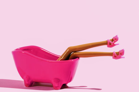 Pink bath with doll legs in pink shoes on pink background.の写真素材
