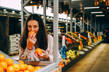 Young beautiful dark-haired woman picks oranges at local farmer's market.の写真素材