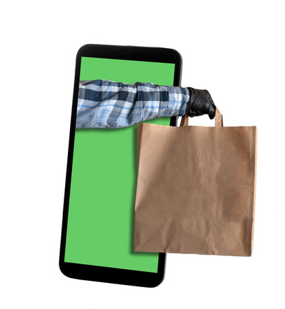 Courier's hand with package sticks out of the mobile phone screen. Concept of online delivery application.の写真素材