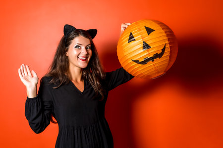 Happy young girl in Halloween costume holding big pumpkin lantern.の写真素材