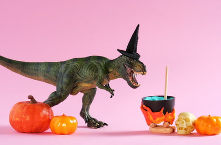 Cute dinosaurs wearing witch hat is brewing potion in pot on pinkの写真素材
