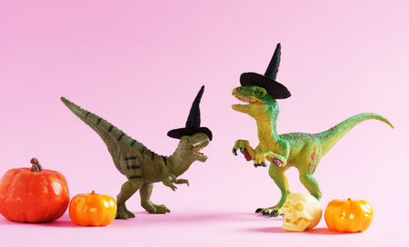 Two cute happy green dinosaurs with pumpkins on pink background.の写真素材